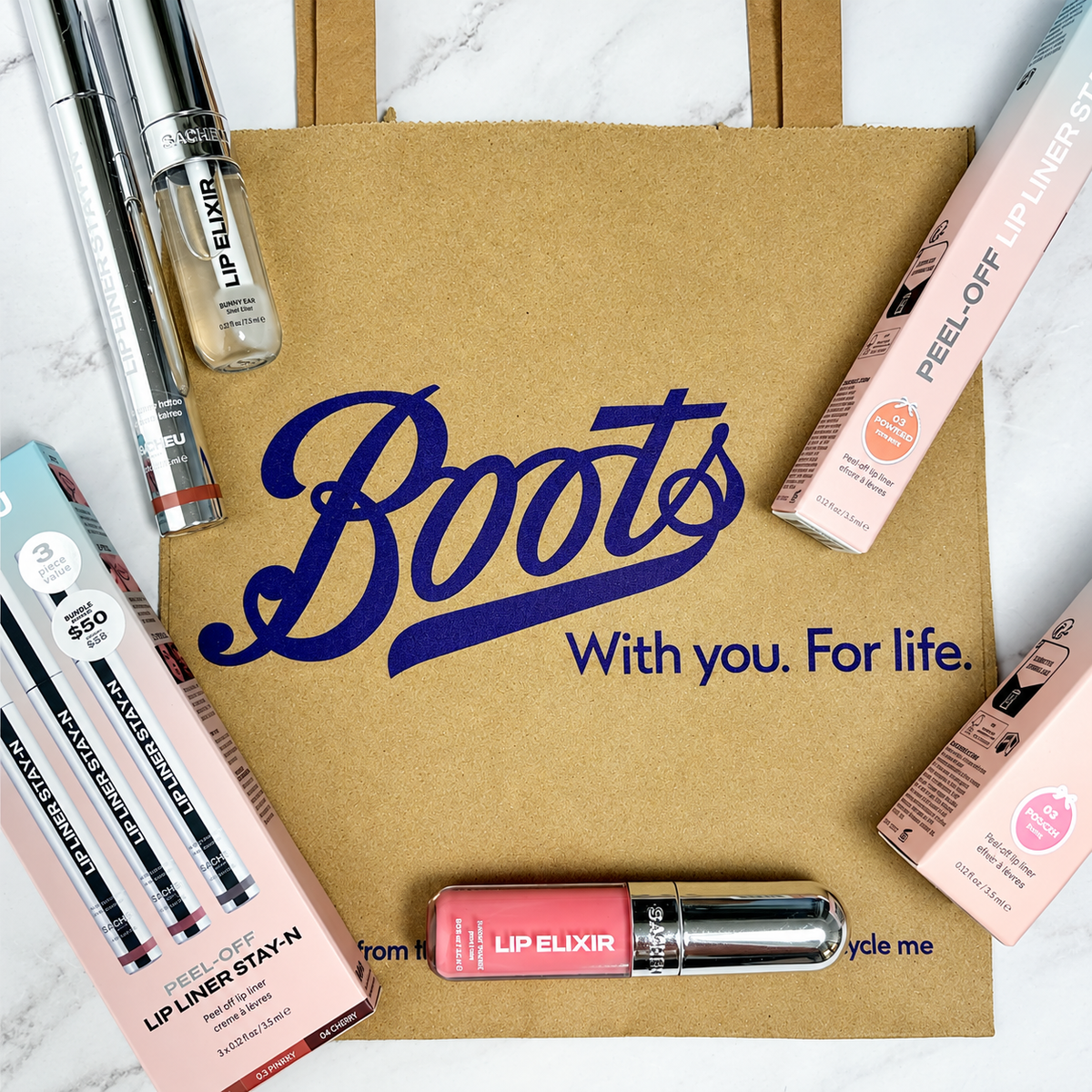 Lip Liner STAY-N® and Lip Glaze Elixir laid out on a Boots shopping bag